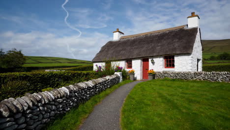 charming thatched cottage with red door and stone wall in rural ireland