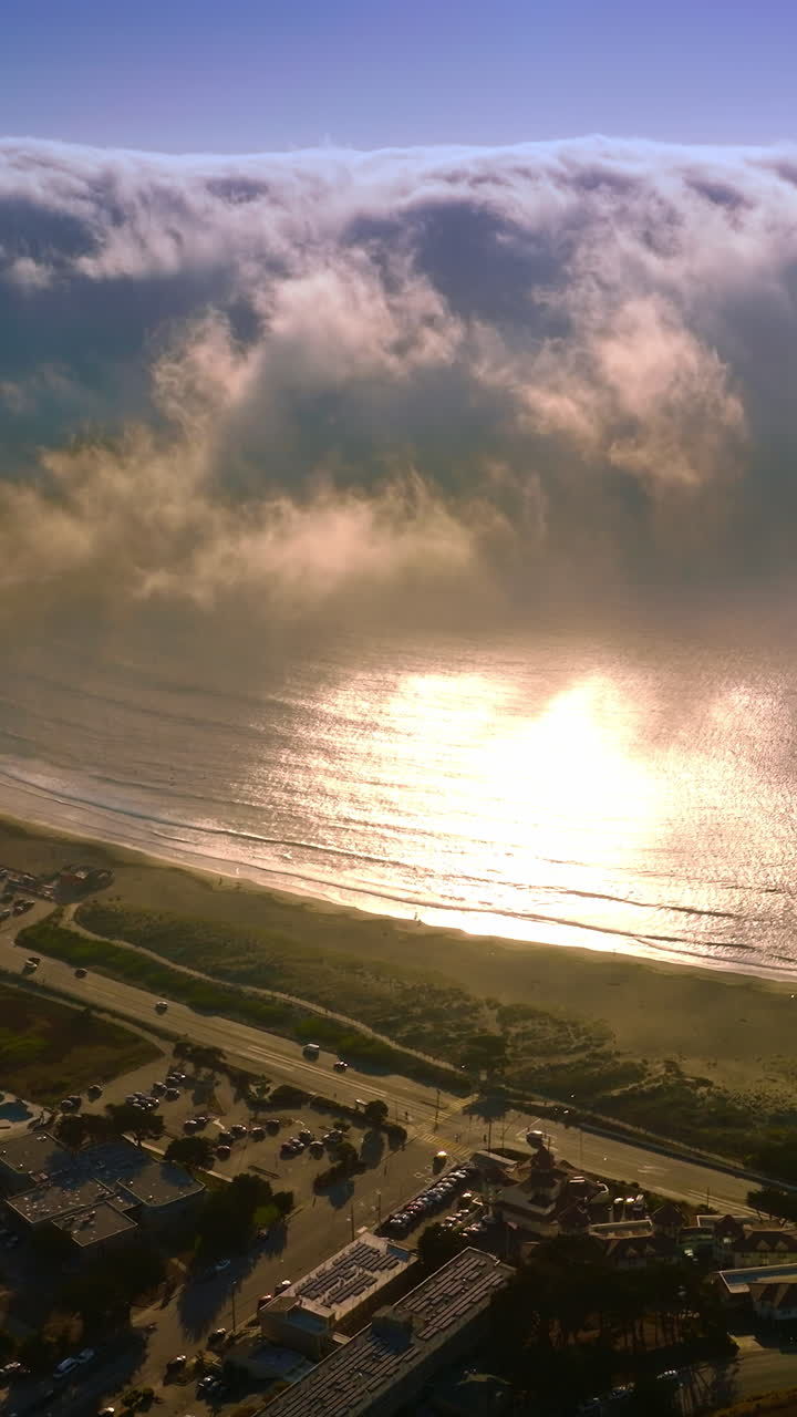 Huge foggy wave approaching the coast of Montara, California, USA from the Pacific. Lovely sunny city at the ocean shore from above. Vertical video