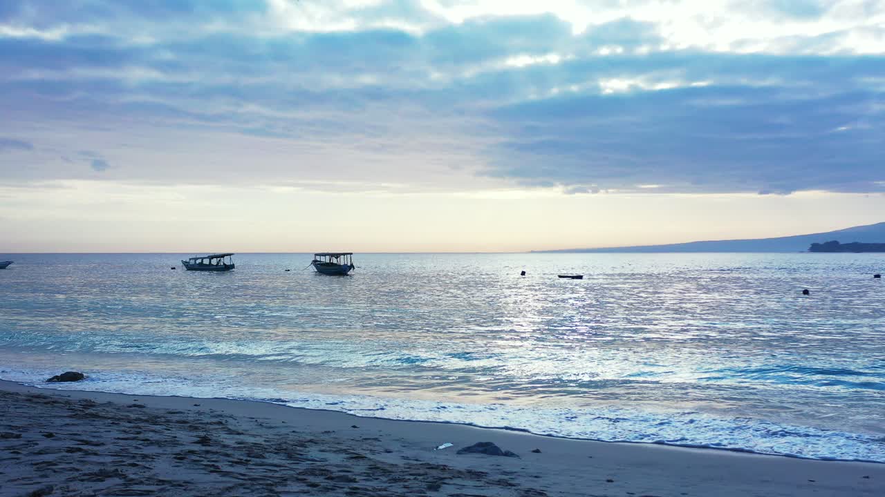 인도네시아 바다 표면에 다채로운 구름이 반사되어 빛나는 하늘과 함께 황혼의 잔잔한 석호에 떠 있는 어선