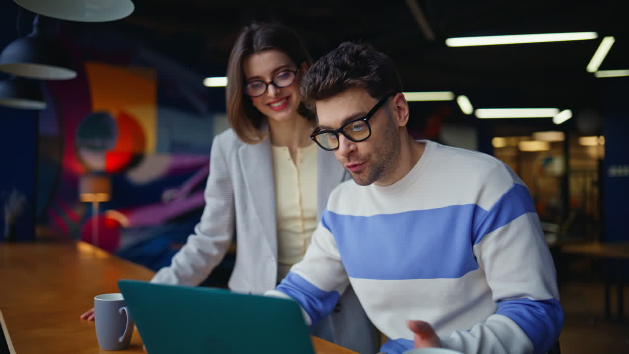 Businesspeople talking virtual meeting looking laptop colourful office closeup