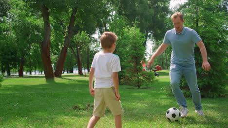 Vater-Spielt-Fußball-Mit-Sohn-Auf-Grünem-Rasen-In-Nahaufnahme.-Papa-Genießt-Das-Spiel-Mit-Dem-Jungen.