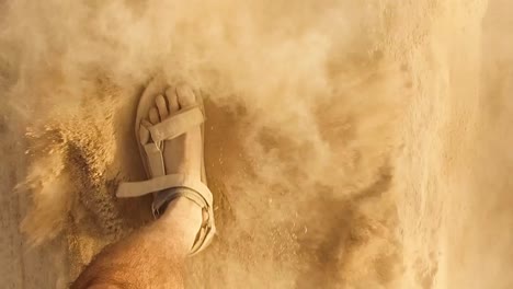 closeup caucasian man's with dusty feet walking slow motion with sandals on sandy desert or beach, footprints kicking some particles sparkling dust sand wearing sandals in sunny day