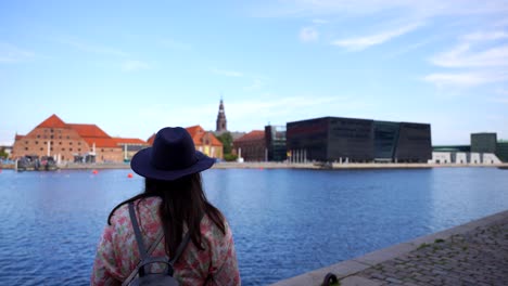 woman by canal taking photos of royal danish library and other iconic copenhagen landmarks