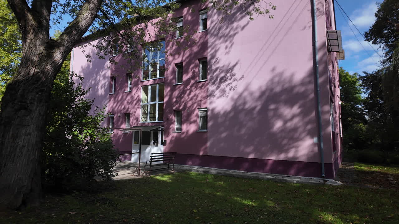 Pink apartment building in shaded green courtyard