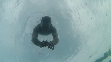 young athletic man swims underwater towards camera slow motion