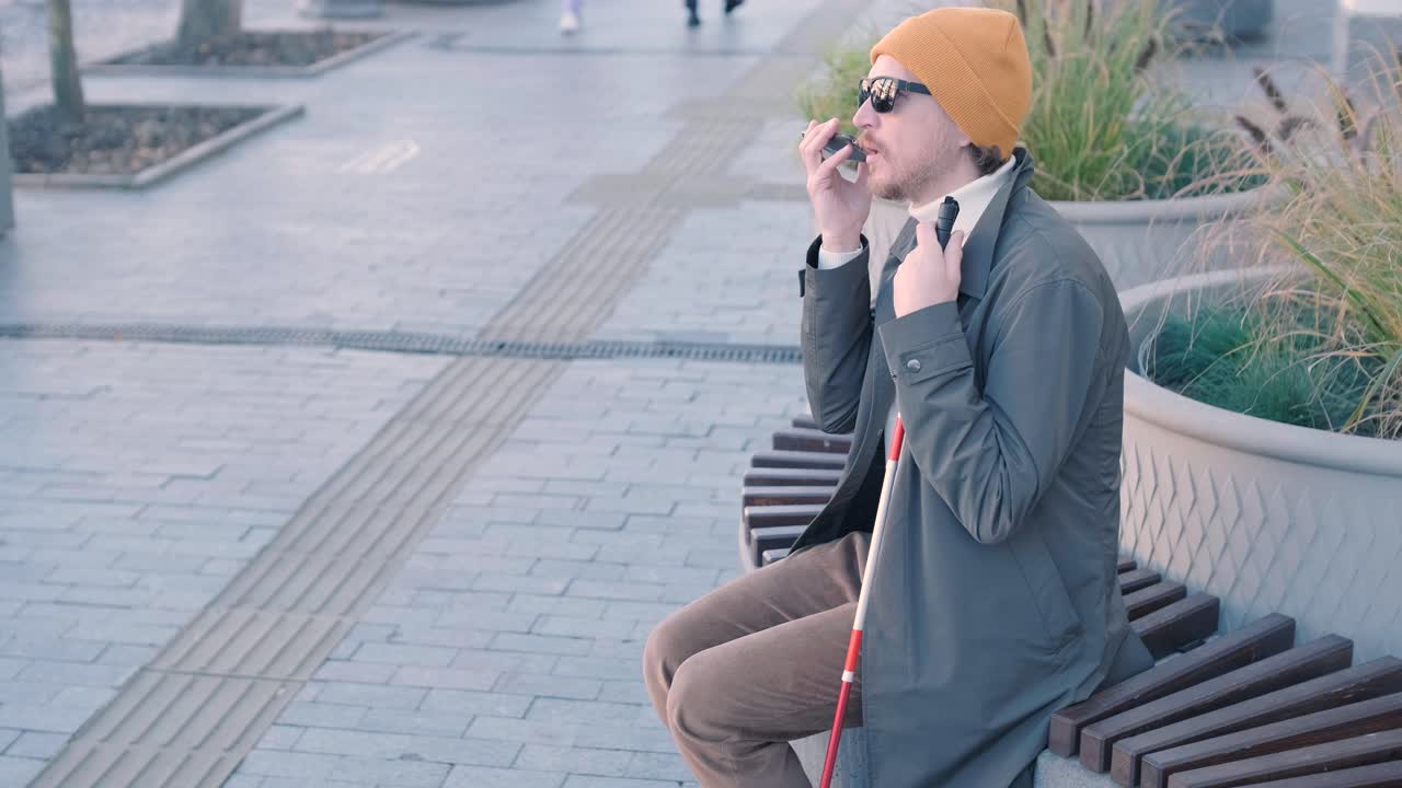 시내의 벤치에 앉아서 전화를 하는 시각장애인.
