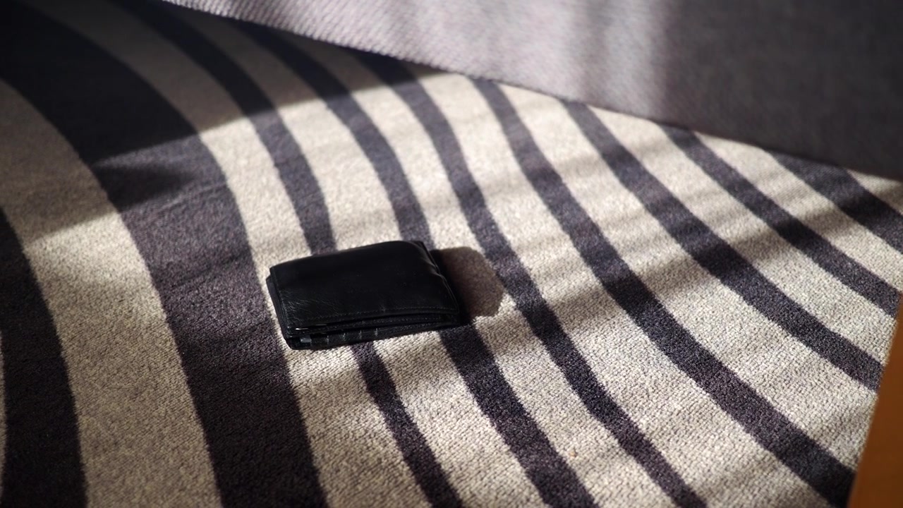 Cartera de cuero negra sobre suelo de moqueta a rayas