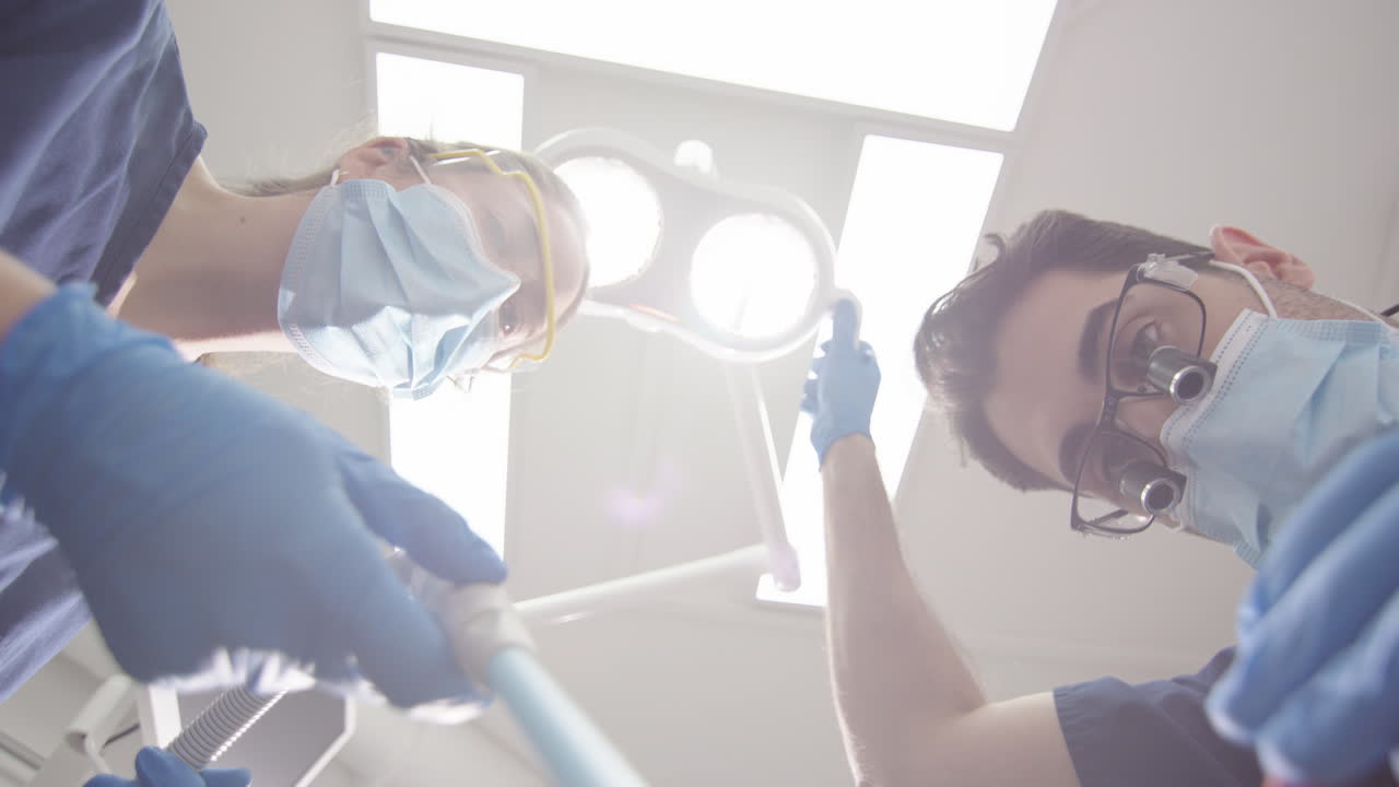 Dental patient upward POV of dentist and assistant with masks doing oral checkup