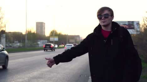 young man hailing a taxi on city street.