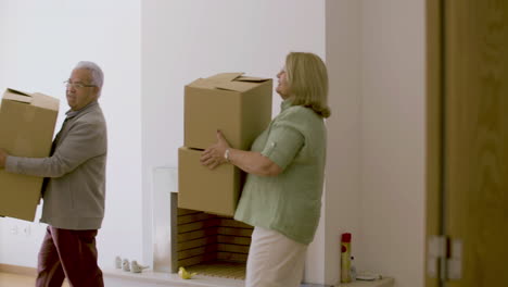 vista lateral de una feliz pareja de ancianos entrando en una nueva casa con cajas de cartón