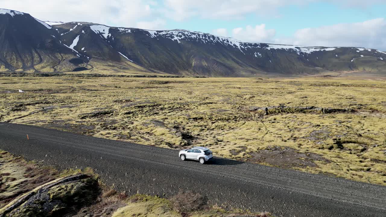 Guidando in Islanda, un SUV percorre una strada sterrata attraverso montagne e paesaggi coperti di muschio