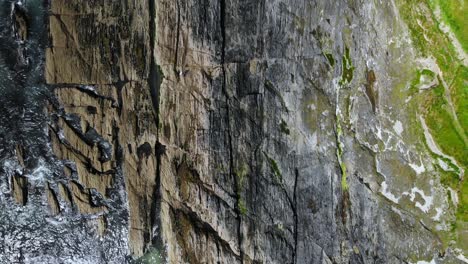 Zerklüftete-Küste,-Felsen-Und-Wellen-Mit-Blauem-Meer-Und-Grünen-Feldern-Aus-Der-Vogelperspektive,-Drohnenaufnahmen