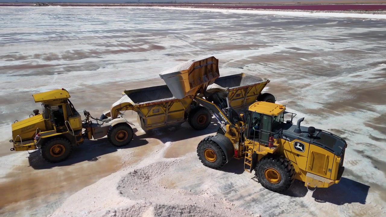 Køretøjer læsser salt på et produktionssted under en klar blå himmel. Walvis Bay, Namibia