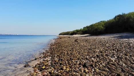 drone flying low by the pebbles on the beach in troia