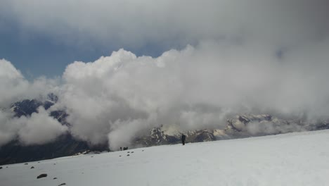 excursionistas en la cumbre de la montaña nevada con nubes