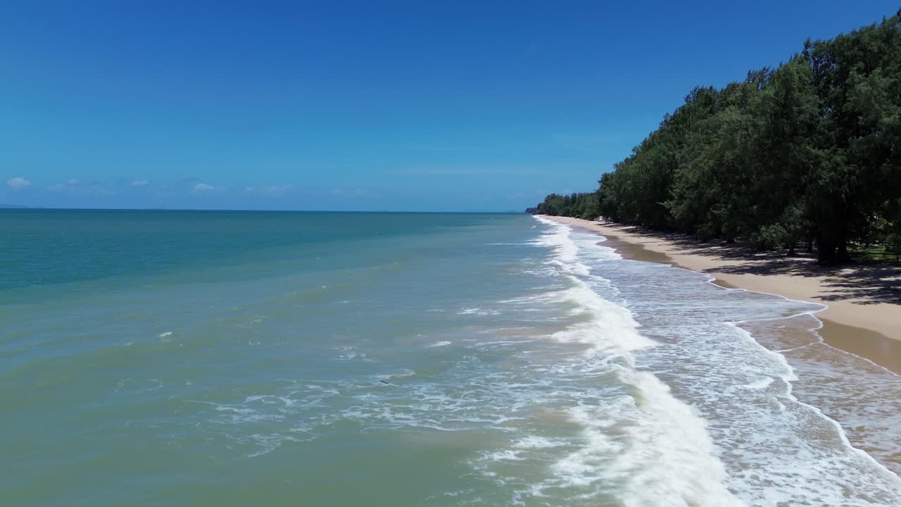 Aerial drone footage of Long Beach in Koh Lanta Thailand showing turquoise ocean, golden sandy coastline, palm and pine trees, tropical vegetation and wide open seascape with no people