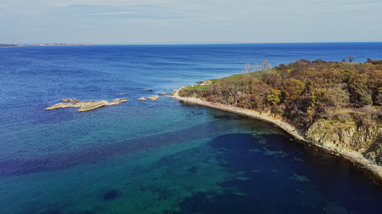 Stunning aerial view of rocky shoreline meeting calm blue waters