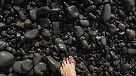 marcher pieds nus en regardant vers le bas avec un point de vue sur une plage de cailloux volcaniques sur l'île de tenerife, playa-de-los-guios