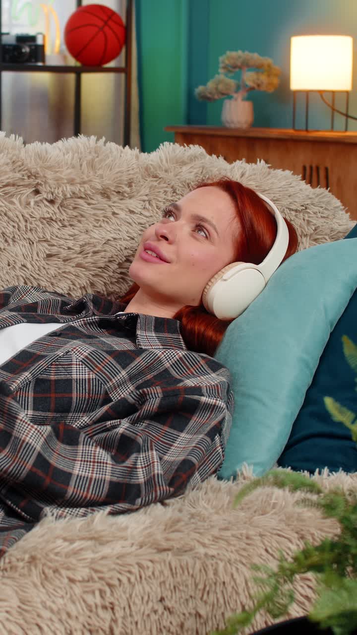 Woman lying on sofa with eyes closed listening to audiobook imagining scenes with peaceful emotion