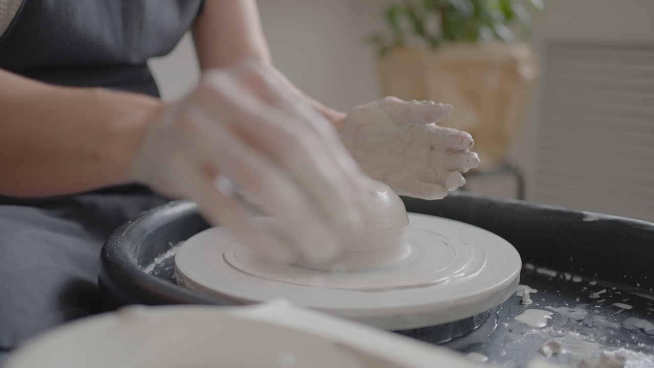 Close-up of the hand of a master working on a potter's wheel for the manufacture of clay and ceramic jugs and plates in slow motion