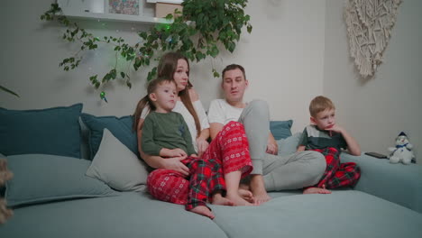 family watching tv. family with children sitting on sofa in living room. high quality 4k footage