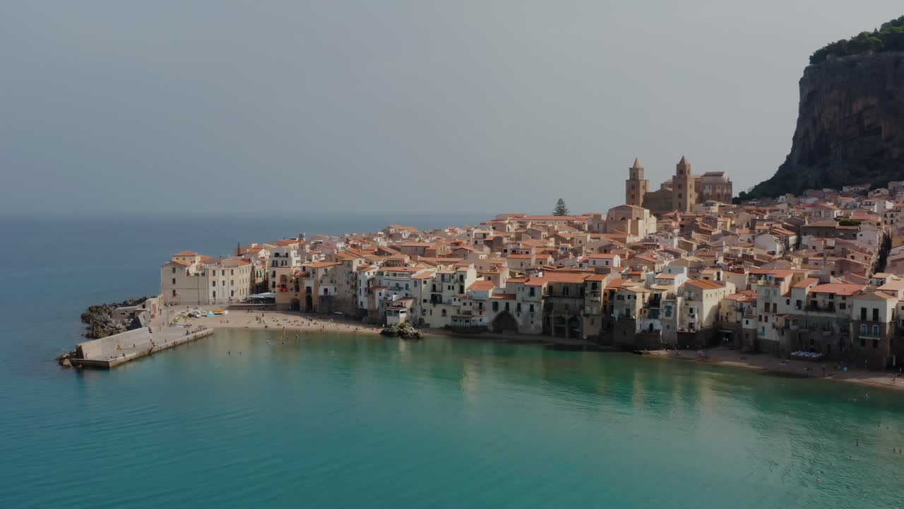 지중해 위에 있는 세팔루 마을로 날아가며, 시칠리아의 샌디 비치 마을의 공중 드론 촬영, 절벽 에 있는 역사적인 이탈리아 마을.