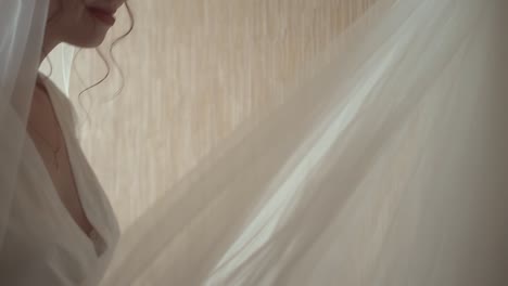 bride looks at wedding dress which hangs on the wall looks at it and is happy smiles close-up