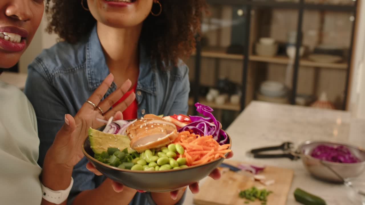 Al abrir la cámara, se ve a varias mujeres compartiendo un poke bowl en la cocina, donde destacan el aguacate y el salmón, con un zoom.