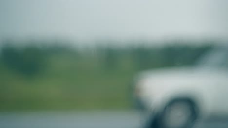 Coche-Borroso-Conduce-Bajo-La-Lluvia-Contra-La-Silueta-Verde