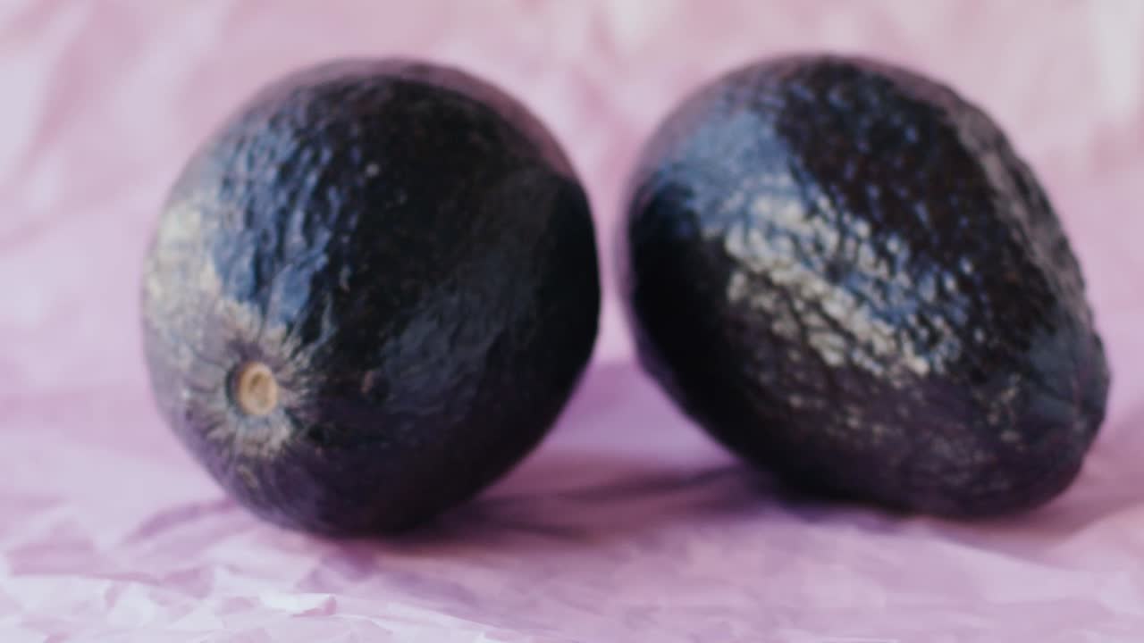 3개의 아보카도가 분홍색 천에 놓여 있고, 두 소녀의 손이 들어와 매우 부드럽게 하나를 찍고, 슬로우 모션 장면과 자연광-1