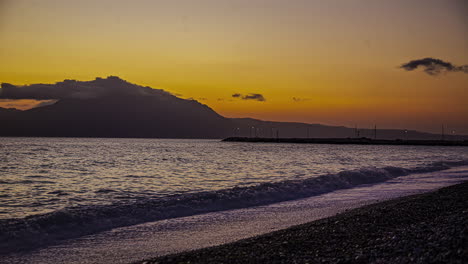 Zeitraffer-Fängt-Strandufer,-Sonnenuntergang-Und-Wolken-Ein,-Die-über-Die-Berge-Ziehen