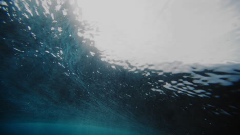 sun light sparkles across edge of textured water rising into barrel at cloudbreak fiji