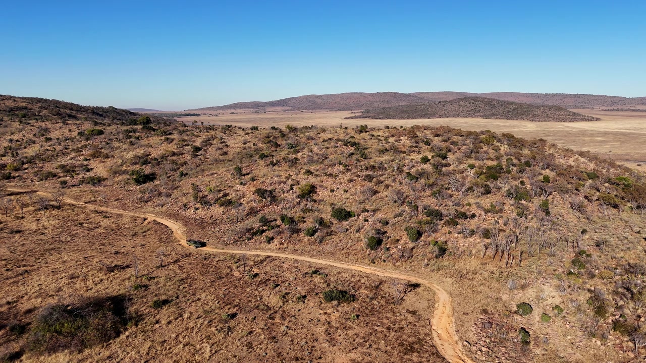 Veicolo utilitario 4x4 percorre una strada sterrata in un passo su terreno roccioso isolato. Vista aerea.