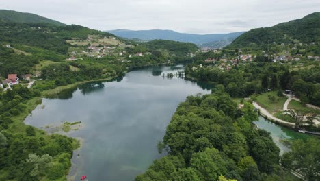 hermoso lago reflectante incrustado en el bosque verde y la ciudad de los balcanes jajce, aérea