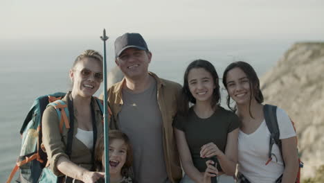 front view of a happy family standing on cliff and smiling at the camera