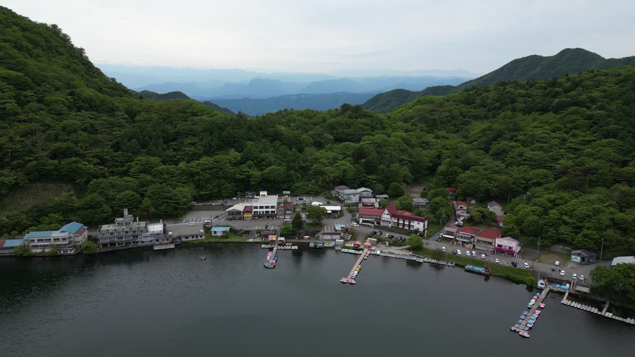 Stunning slow motion push in drone shot over small Japanese town on lake shore