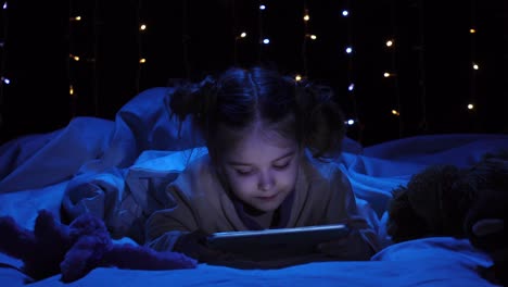 niño jugando con la tableta por la noche