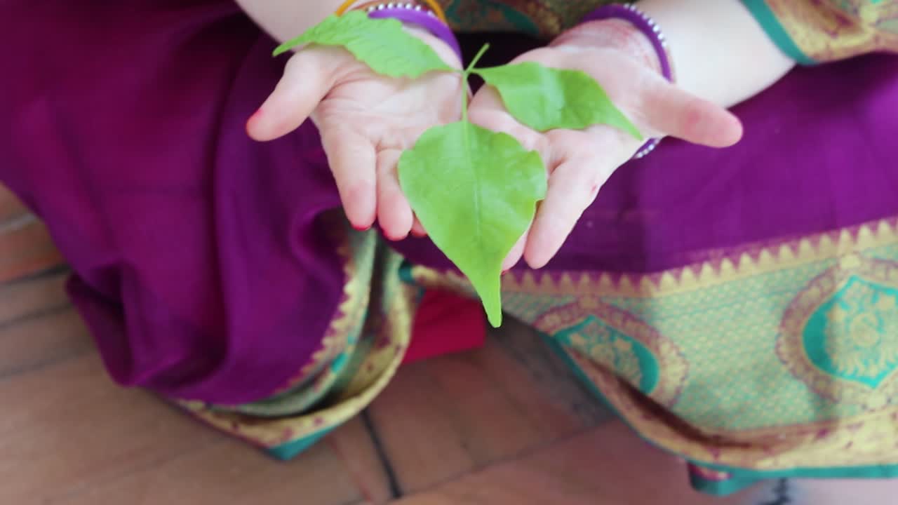 낮에 다른 각도에서 성스러운 에글 마멜로스 또는 바엘 잎을 손에 들고 있는 신도