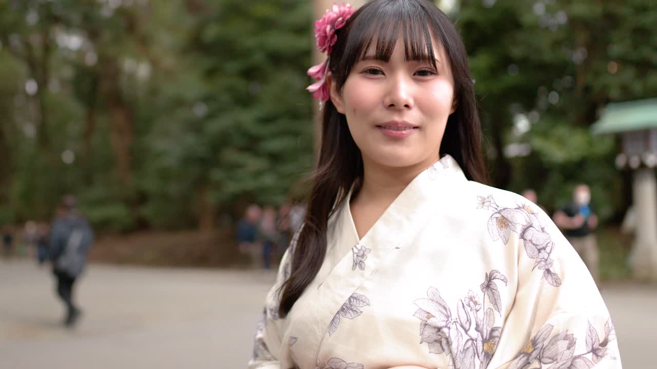 Una donna in yukata floreale sta davanti a un grande torii di legno a Tokyo.