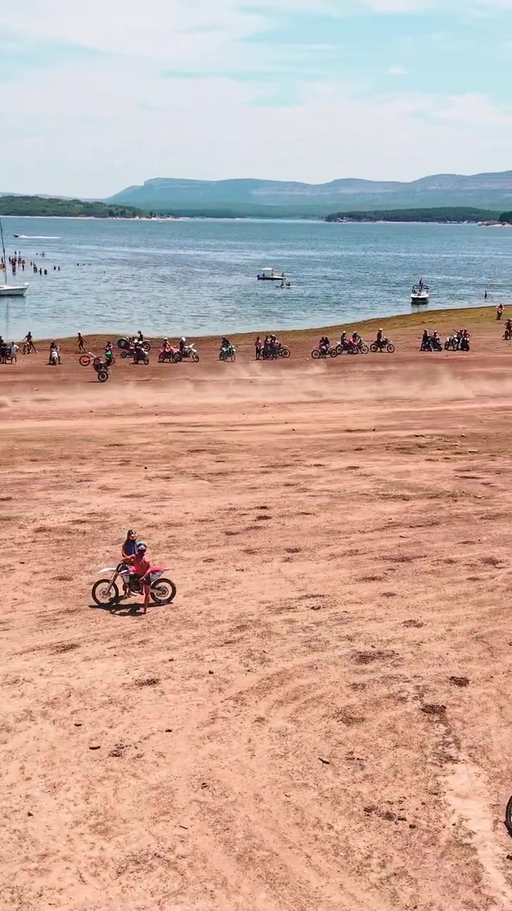 Gruppo di piloti di motocross in gara su pista sterrata vicino al lago