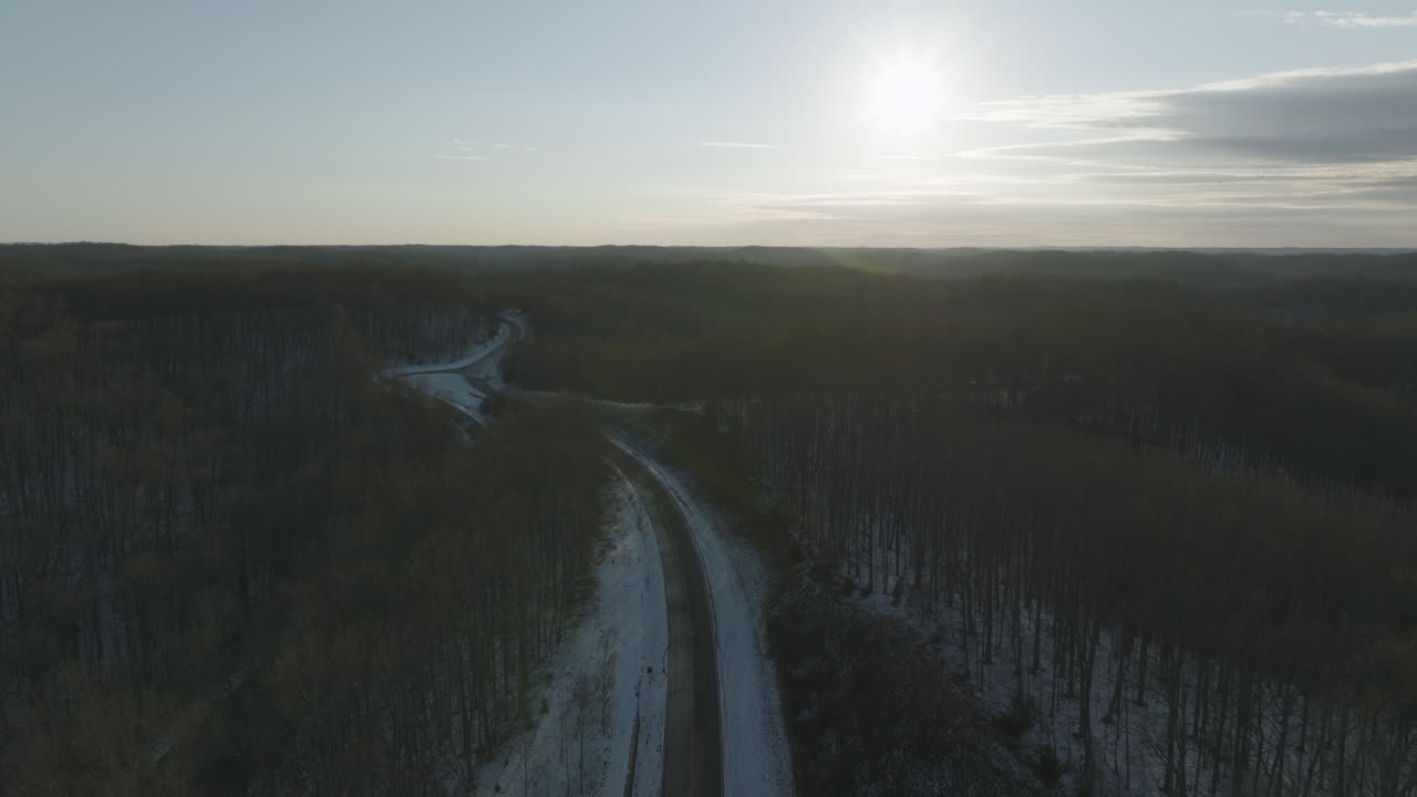 Natchez Trace Scenic Highway, covered in ice and snow, runs through forest at sunset, aerial view, Franklin Tennessee.