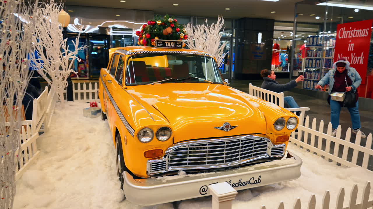 New York, USA, 5. Dezember 2025: Gelbes Vintage-Taxi mit Weihnachtsbaum zur Schau gestellt. Ein klassisches gelbes Checker-Taxi wird in einer weihnachtlichen Umgebung mit einem Weihnachtsbaum auf dem Dach und Geschenken im Kofferraum ausgestellt.