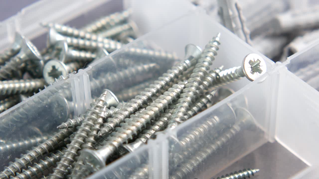 tornillos variados en una caja de almacenamiento de plástico transparente