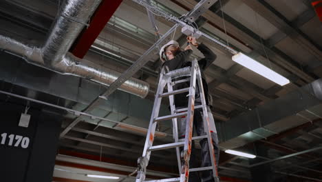 electrician installing ceiling light fixture