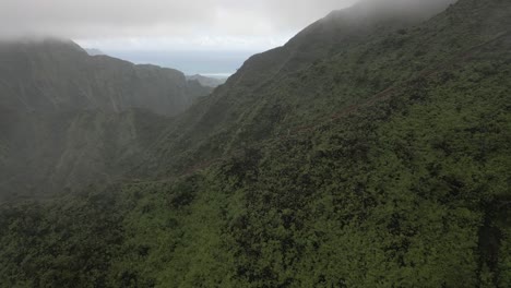 mountain fog aerial flies over hikers descending ridge trail on oahu