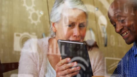 digital icons against senior couple using digital tablet