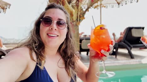 a beautiful woman in a bikini posing with a summer cocktail by the pool