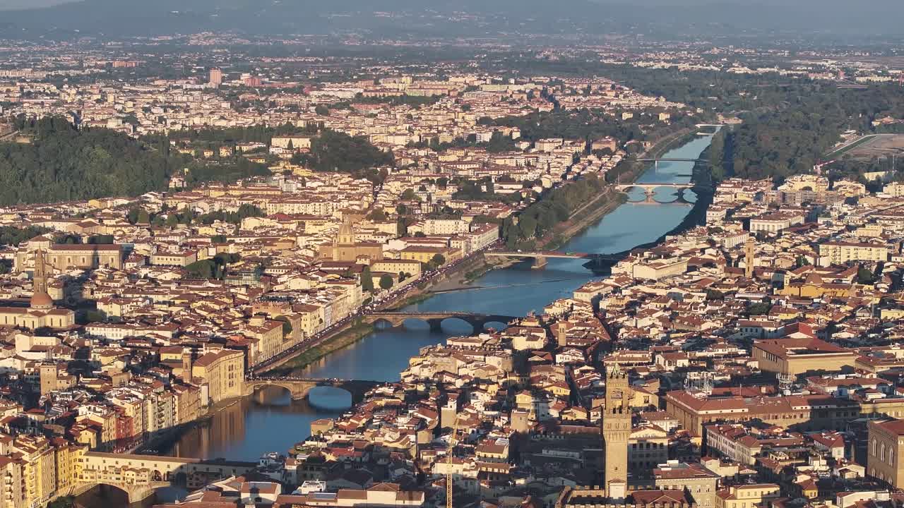 Dynamic high-angle drone view slowly panning across Florence's historic center, showcasing the medieval Ponte Vecchio bridge and the Arno River at vivid daytime