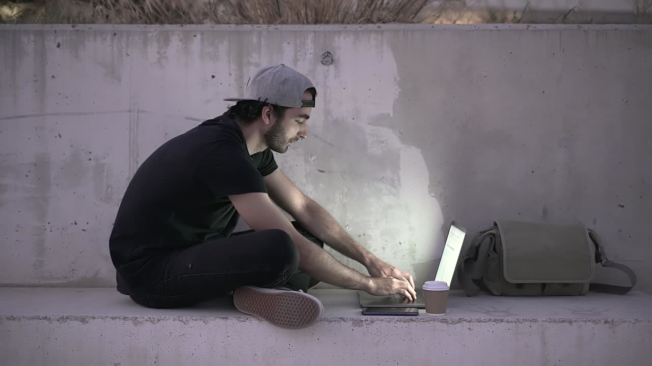 Mann jobber på laptop utendørs om natten
