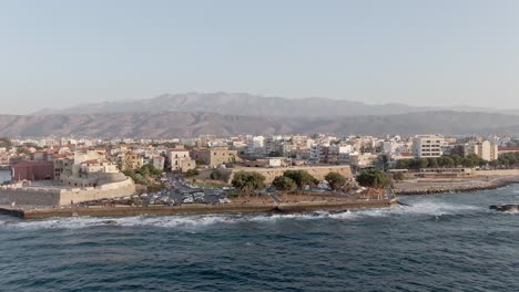 Distrito-De-Edificios-De-Apartamentos-En-La-Costa-Del-Mar-En-La-Ciudad-De-Chania,-Creta,-Vista-Aérea-De-Drones-Con-Efecto-De-Vértigo